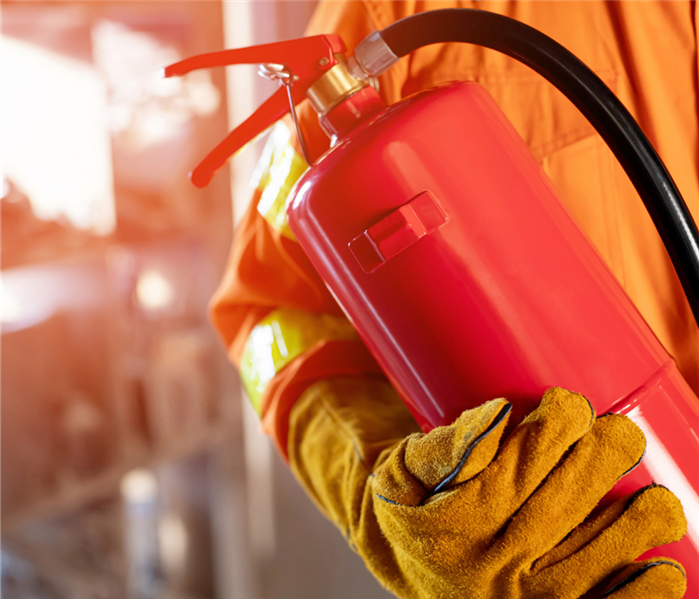 A firefighter stands with a fire extinguisher in a home.