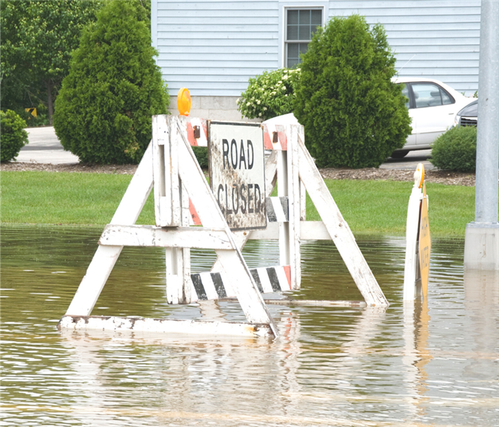 'Road Closed' sign in flooded waters.