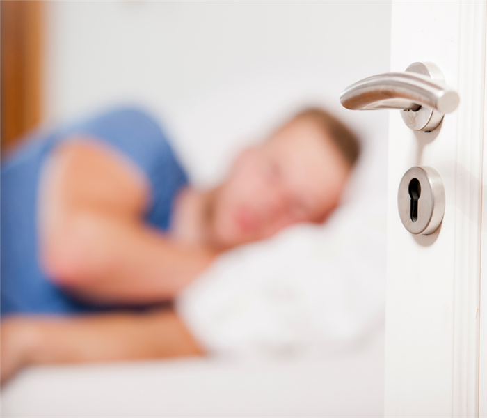 Picture shows a man sleeping with a door open